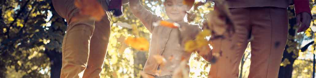 A family kicks up leaves on a sunny fall day